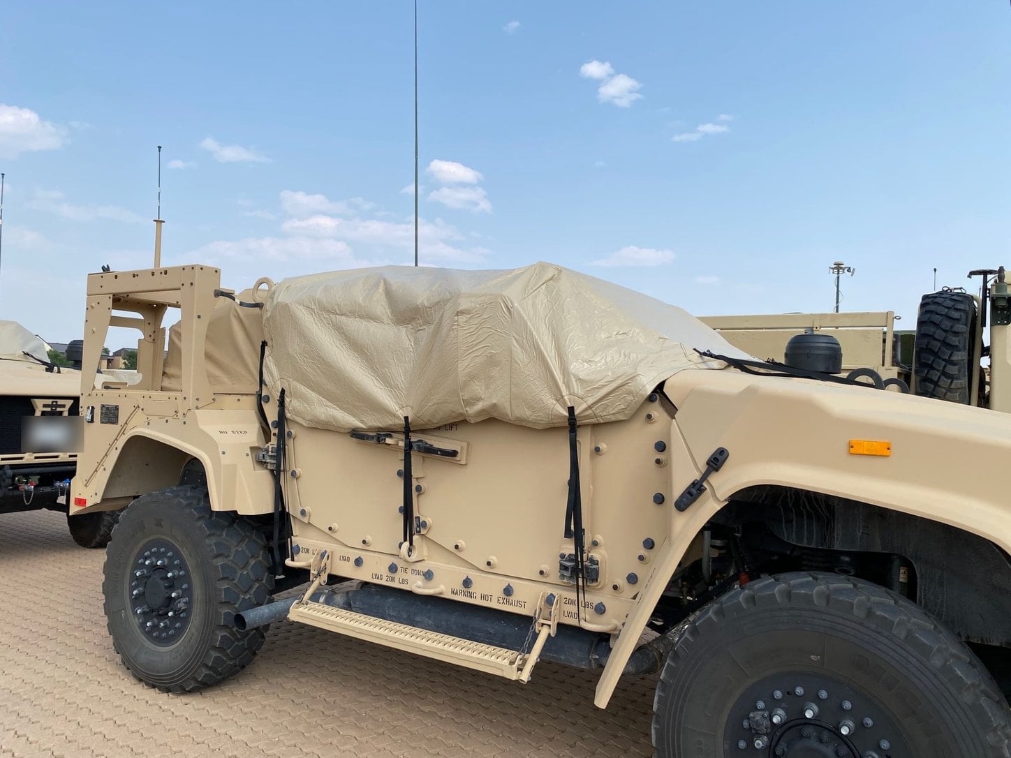 Custom fitted tan cover strapped over the cargo bed of a military tactical vehicle